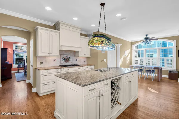 a kitchen with stainless steel appliances granite countertop a sink a stove and a wooden floors