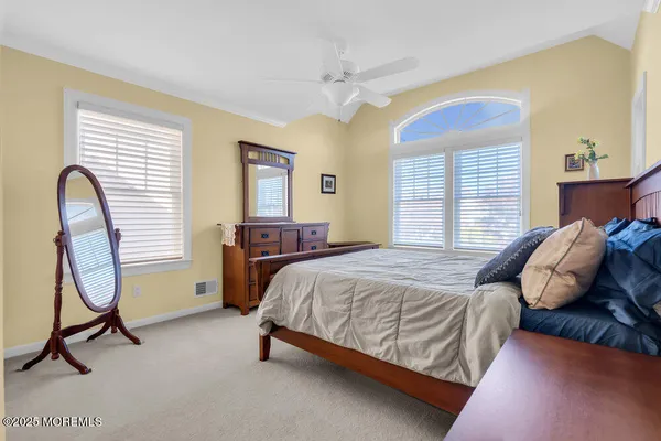 a bedroom with a bed a desk and windows