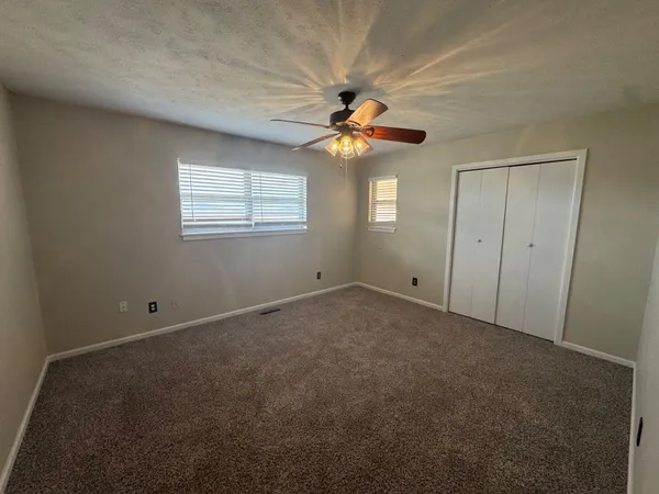 an empty room with windows and fan