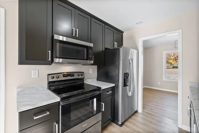 an empty room with wooden floor ceiling fan and windows