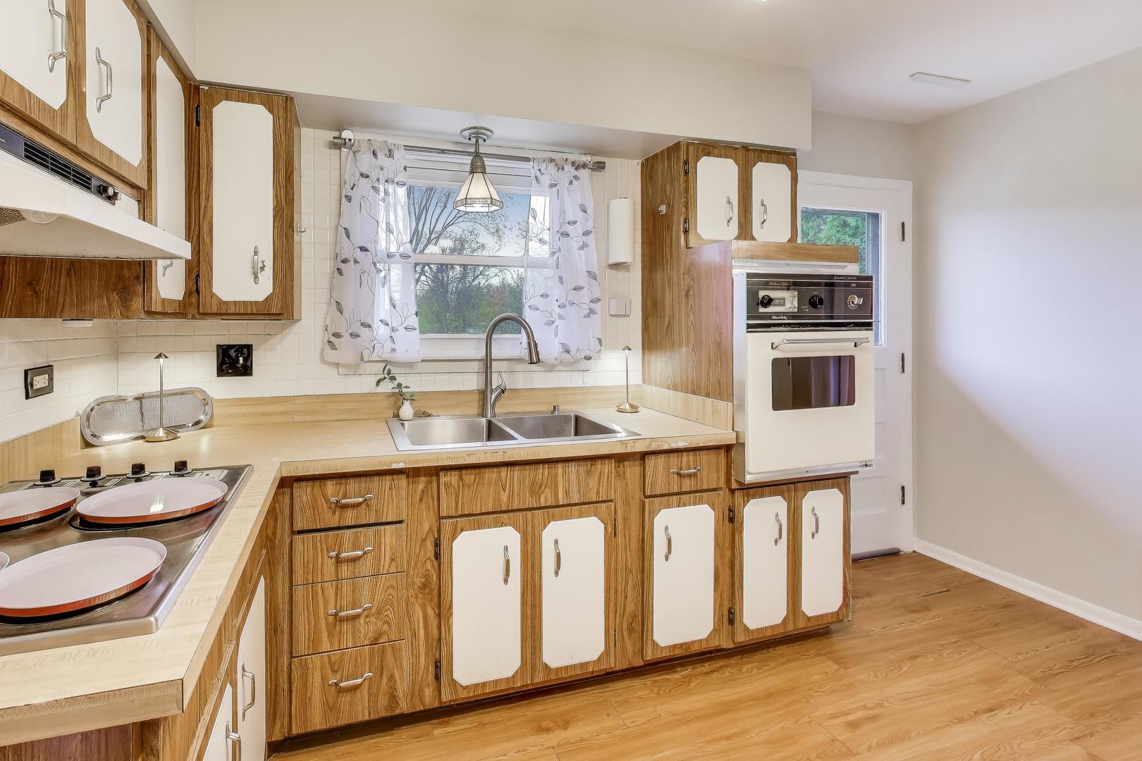 400 Landmeier Road Elk Grove Village, IL 60007 - Photo 11 of 33 a white kitchen with a sink a stove and wooden floor