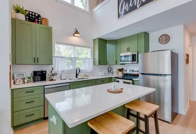 a kitchen with a refrigerator a stove a sink cabinets and a dining table