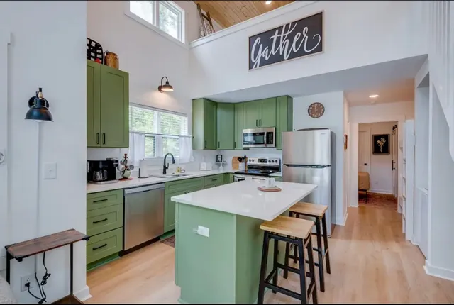 a kitchen with stainless steel appliances kitchen island a table chairs and a refrigerator