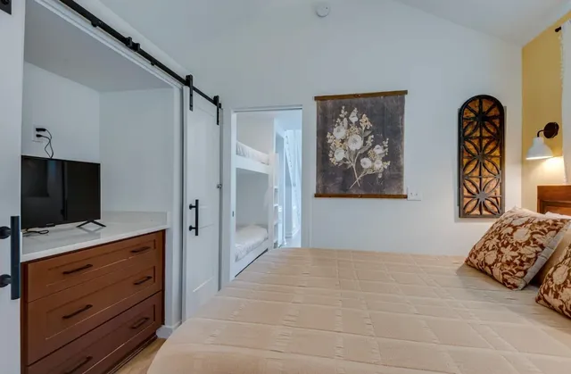 a bedroom with bed and a flat tv screen on dresser