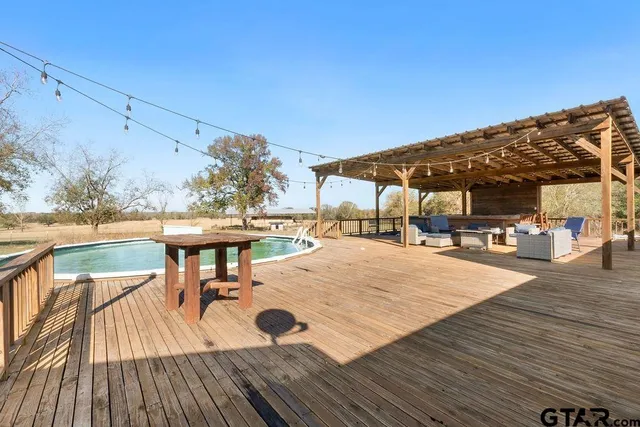 a view of a patio with table and chairs a barbeque with wooden floor and fence