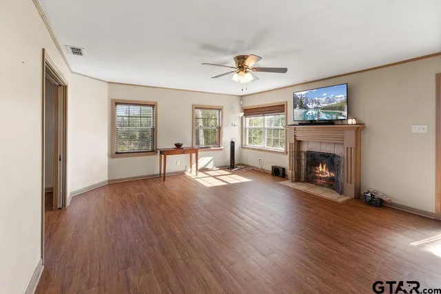 a view of a livingroom with wooden floor a ceiling fan and windows