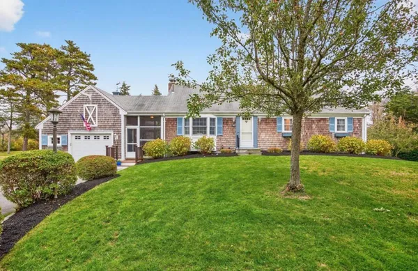 a view of house in front of a big yard with large trees