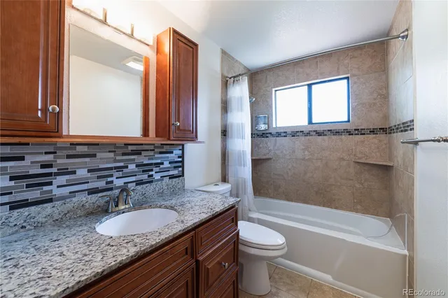 a bathroom with a granite countertop sink toilet and shower