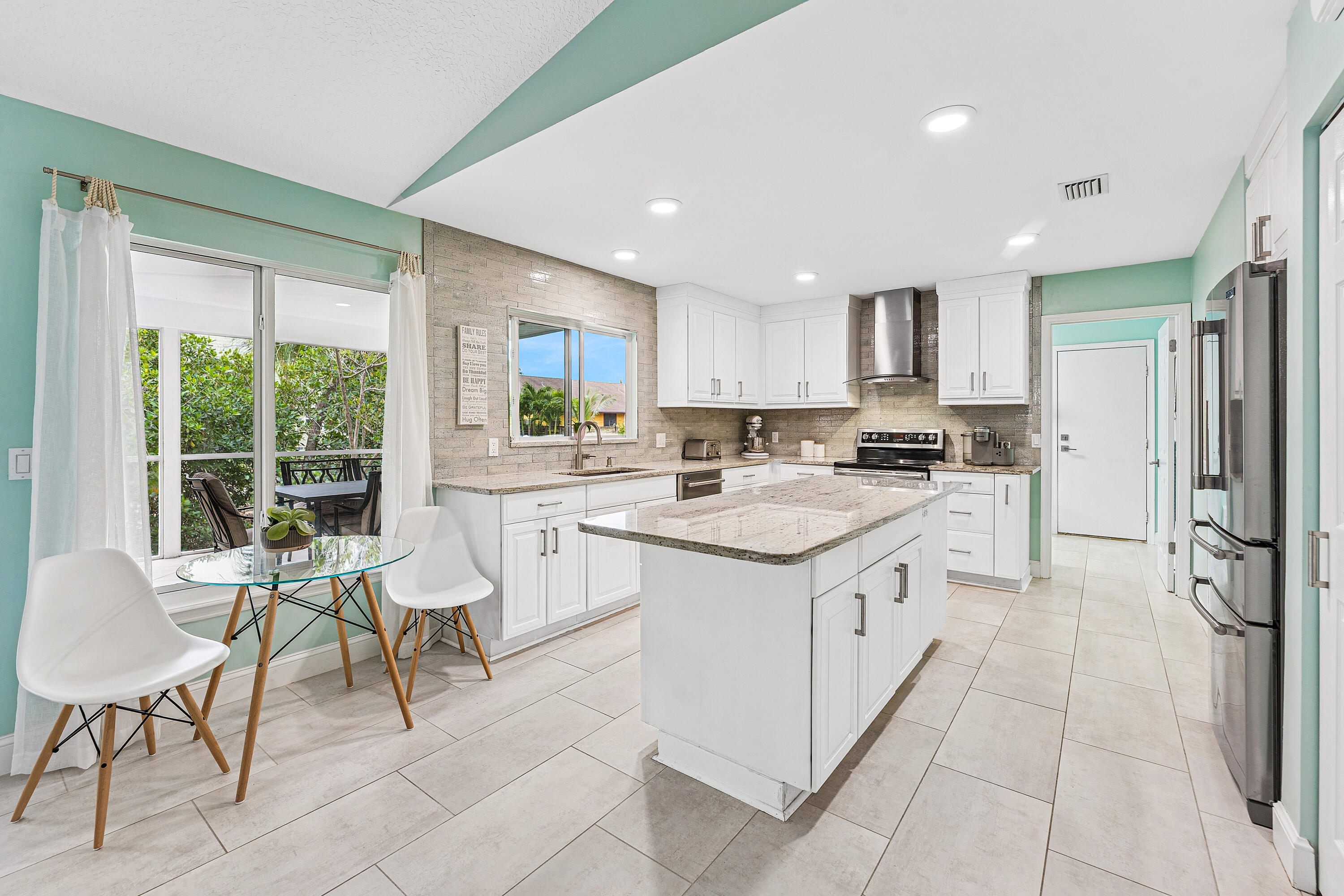 709 Warren Drive Jupiter, FL 33458 - Photo 5 of 56 a kitchen with a sink chairs and white appliances