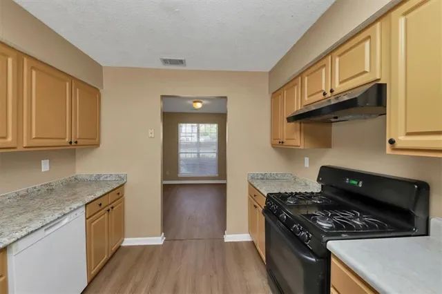 a kitchen with stainless steel appliances granite countertop a refrigerator a sink a stove and a window