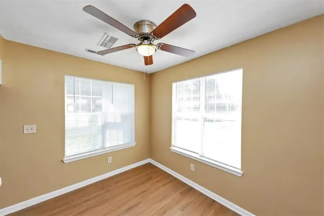 an empty room with wooden floor fireplace and windows