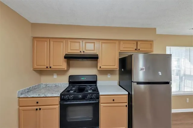 a kitchen with granite countertop wooden cabinets and a stove top oven