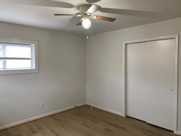 an empty room with a window and a fan