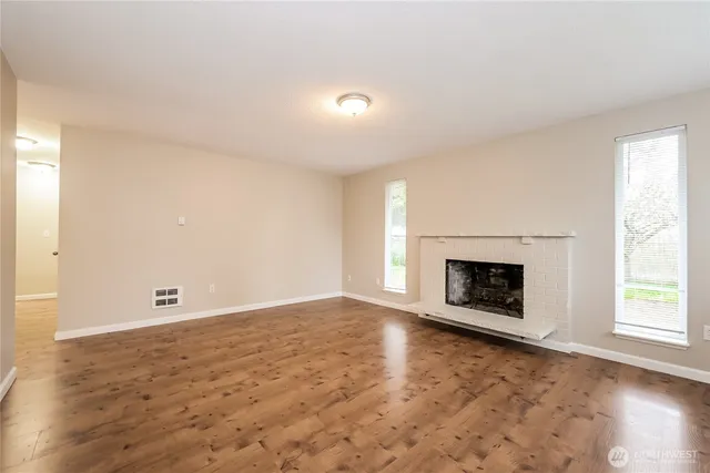 an empty room with windows and fireplace