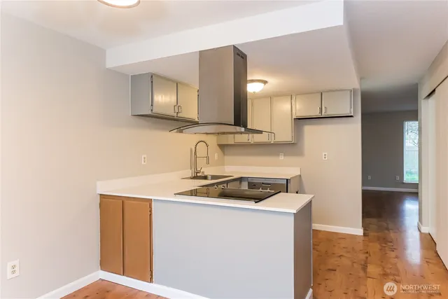 a kitchen with a sink a stove cabinets and a wooden floor