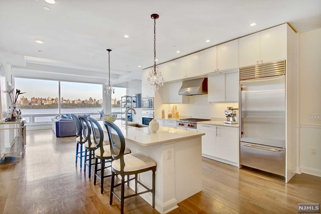 a kitchen with kitchen island a large counter top space appliances and a view of living room