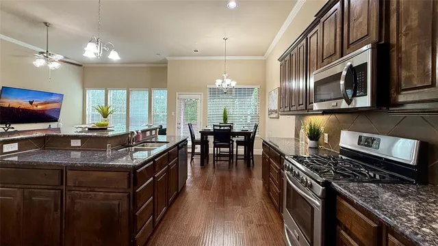 a kitchen with stainless steel appliances granite countertop a stove a sink dishwasher a dining table and chairs with wooden floor