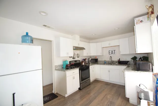 a kitchen with a sink a stove a refrigerator and white cabinets
