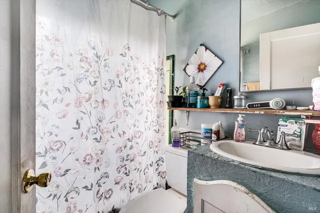a bathroom with a granite countertop sink and a toilet