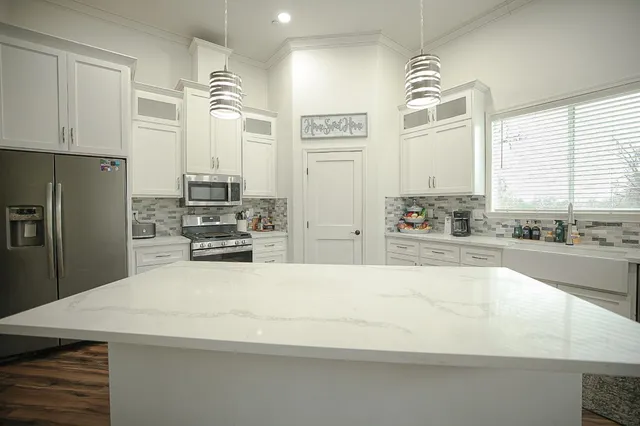 a large kitchen with kitchen island a large counter top space a sink stainless steel appliances and cabinets