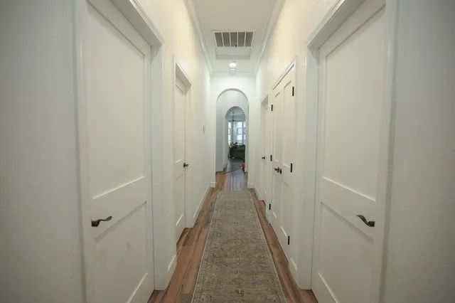 a view of a hallway with wooden floor and a bathroom