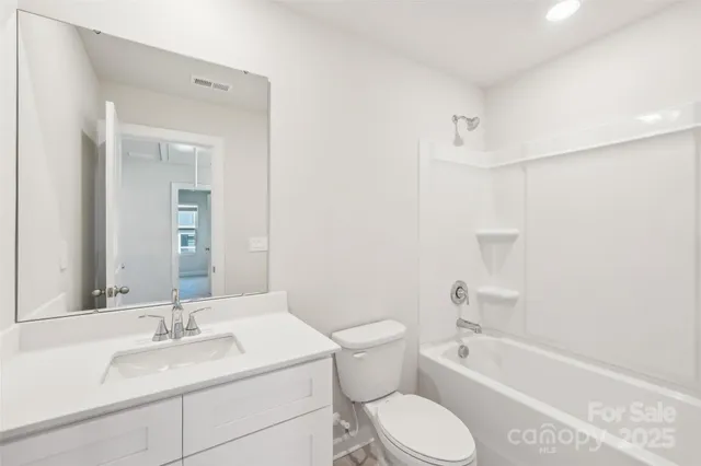a bathroom with a granite countertop sink toilet mirror and bathtub