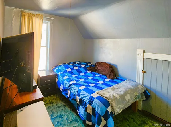 a bedroom with a bed and a flat tv screen on dresser