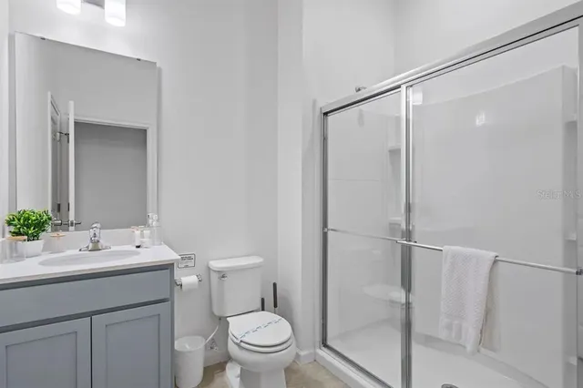 a bathroom with a shower sink vanity mirror and toilet