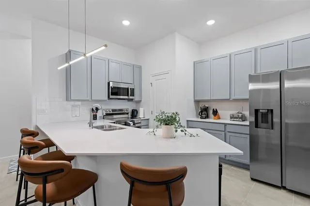 a kitchen with stainless steel appliances a sink a microwave a refrigerator and chairs