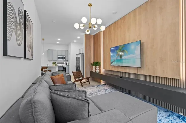 a living room with furniture a chandelier and a flat screen tv