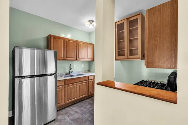 a kitchen with stainless steel appliances granite countertop a refrigerator a stove a sink dishwasher and wooden cabinets