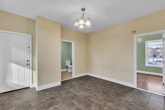 a view of an empty room with window and chandelier fan