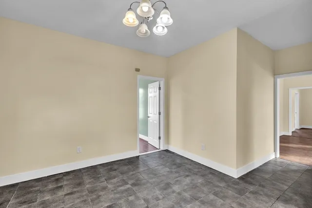 an empty room with a chandelier fan and windows