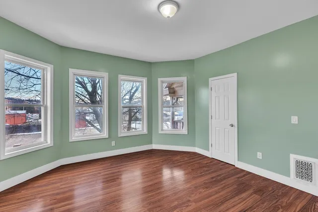 a view of an empty room with window and wooden floor