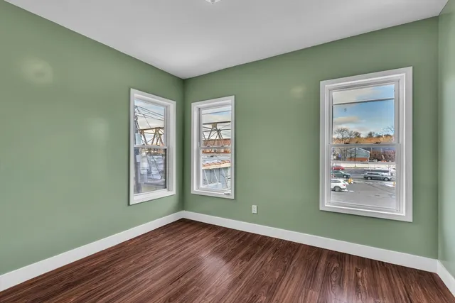 a view of an empty room with window and wooden floor