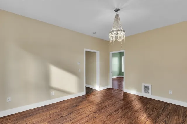 a view of a hallway with wooden floor and a chandelier