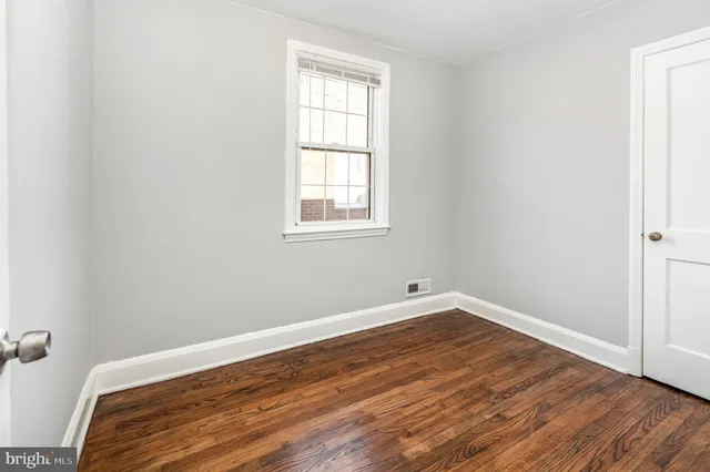 an empty room with wooden floor and a window