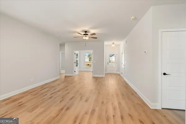 a view of kitchen and empty room with wooden floor