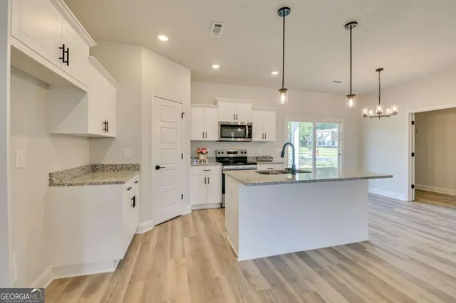 a kitchen with stainless steel appliances granite countertop a refrigerator a stove a sink dishwasher and a wooden floor