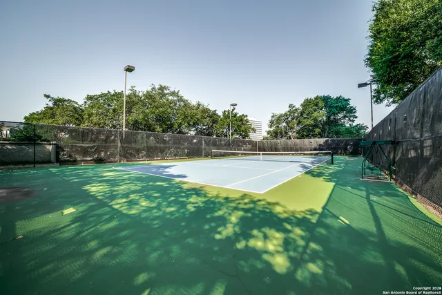 a view of a swimming pool with a bench and trees in the background