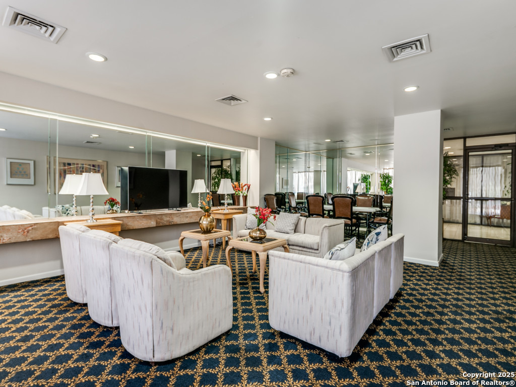 7701 Wurzbach Road, Unit 806 San Antonio, TX 78229 - Photo 7 of 20 a living room with kitchen island a flat screen tv and a table