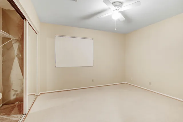 an empty room with a ceiling fan and window