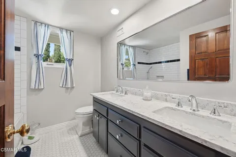 a bathroom with a granite countertop sink mirror vanity and toilet