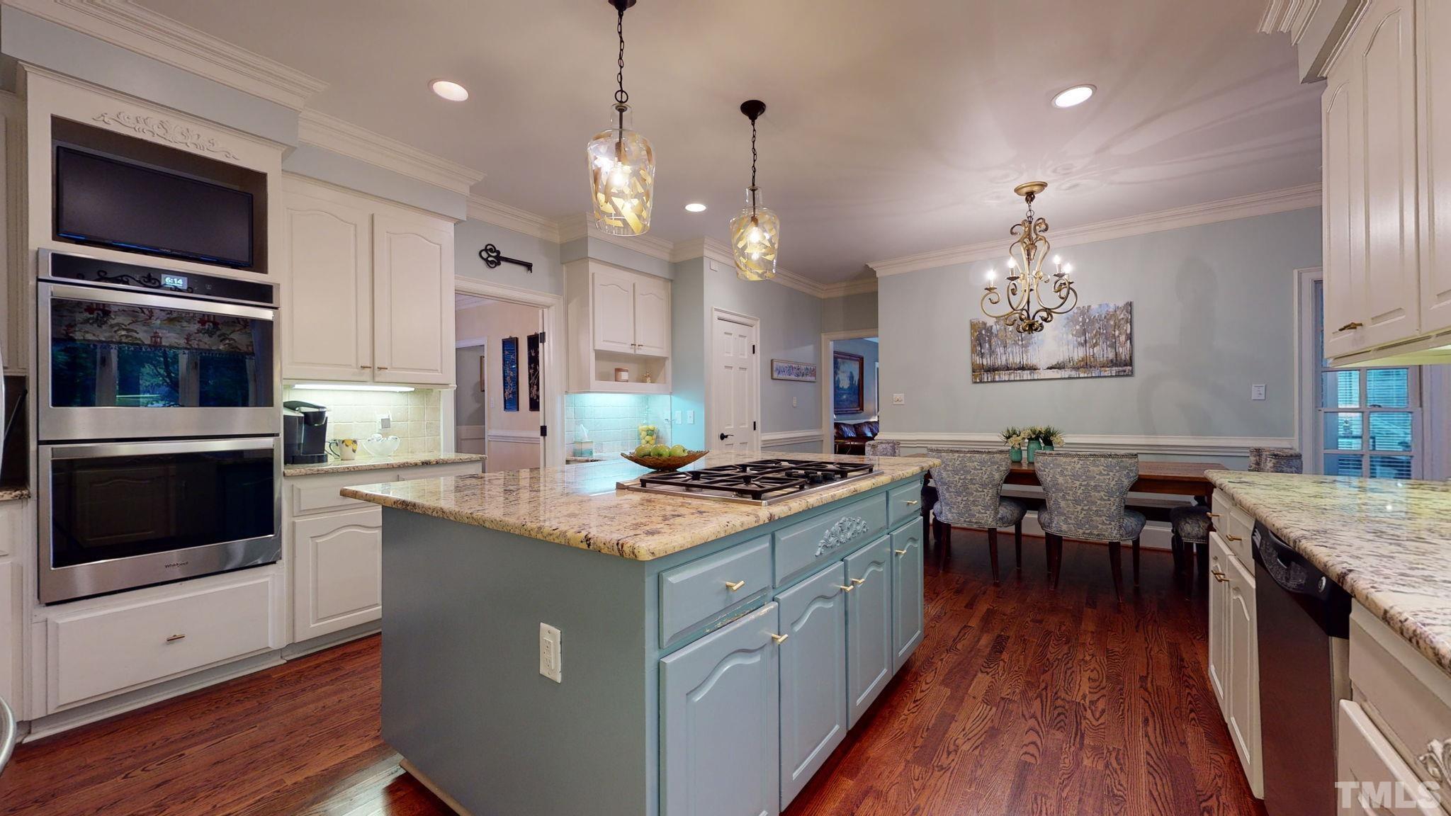 7313 Rainwater Road Raleigh, NC 27615 - Photo 13 of 30 a kitchen with stainless steel appliances granite countertop a stove top oven a sink dishwasher a dining table and chairs with wooden floor