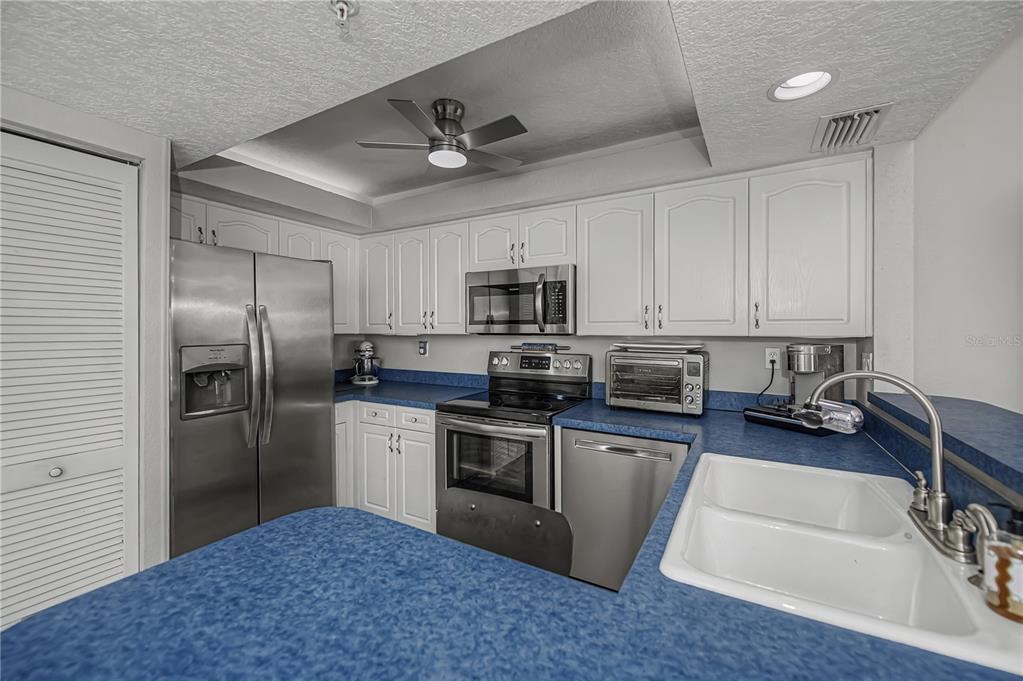 2255 North Beach Road, Unit 20 Englewood, FL 34223 - Photo 23 of 50 a kitchen with stainless steel appliances granite countertop a sink a stove a refrigerator cabinets and a dining table with wooden floor