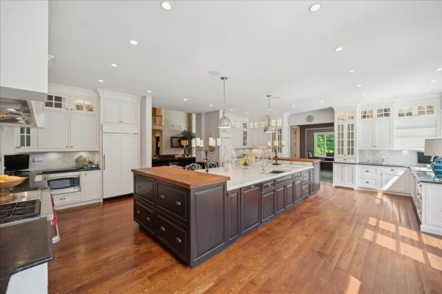 a large kitchen with stainless steel appliances a stove a sink dishwasher and a oven with white cabinets