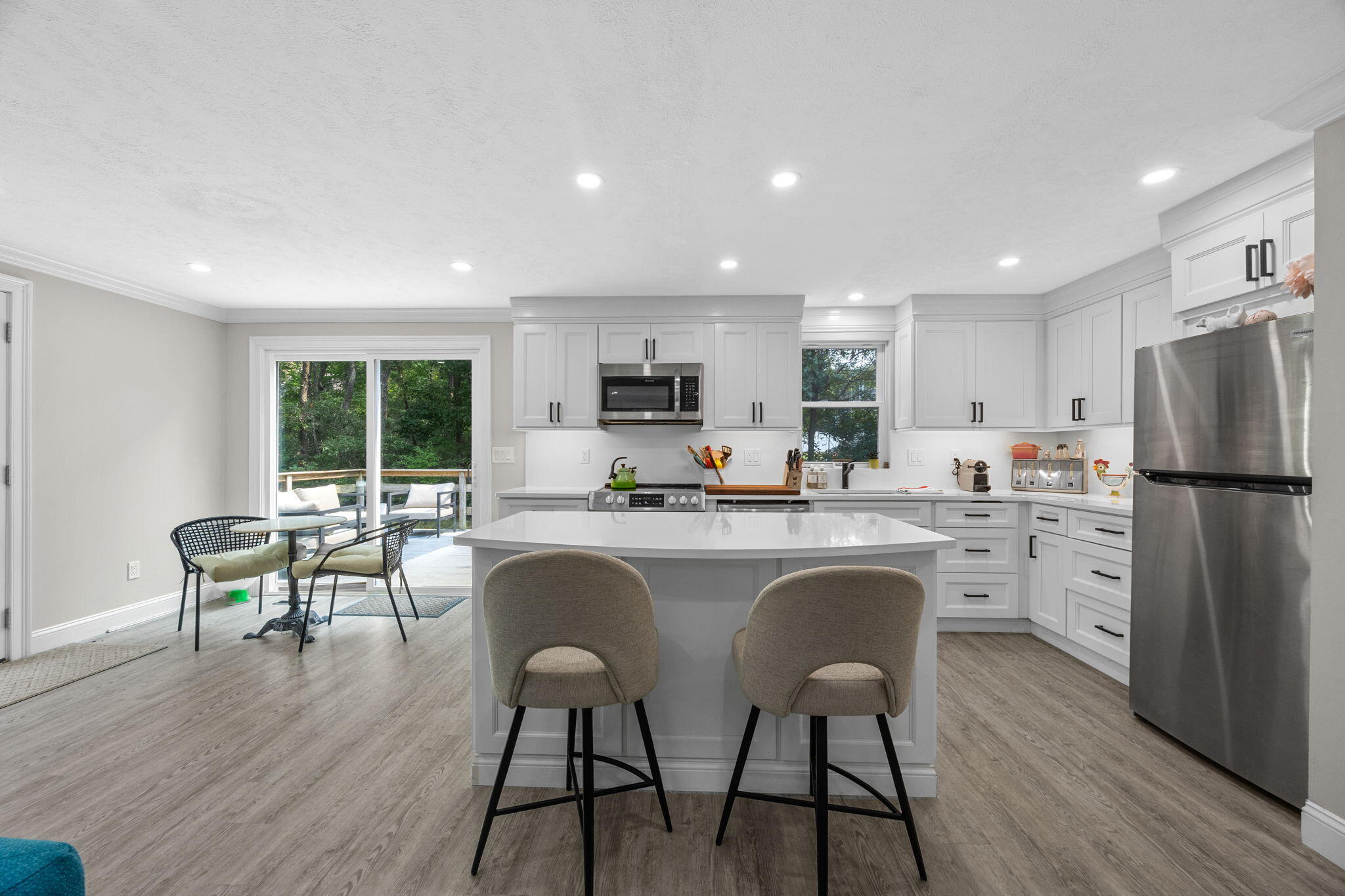 140 Noisy Hole Road Mashpee, MA 02649 - Photo 9 of 53 a kitchen with stainless steel appliances granite countertop a table chairs refrigerator a sink dishwasher and microwave with wooden floor