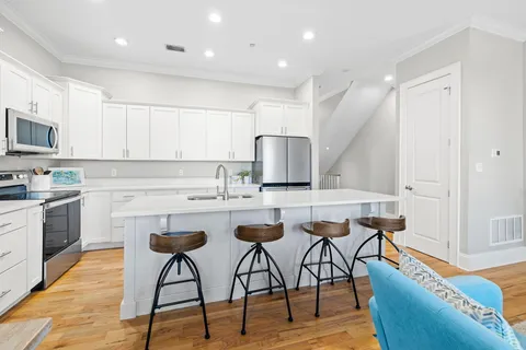 a kitchen with a sink and a stove top oven with white cabinets