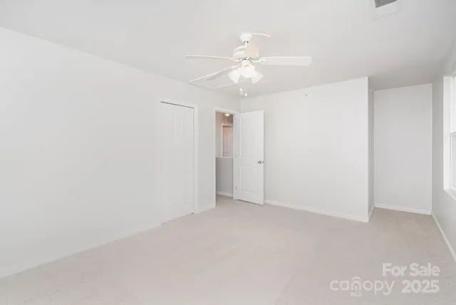 an empty room with a chandelier fan and closet