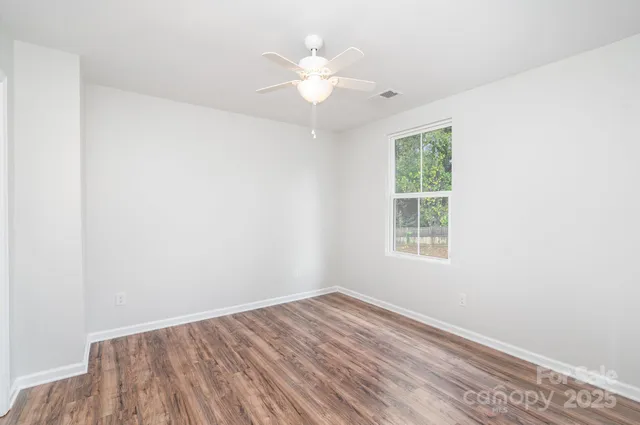 an empty room with a window and a ceiling fan
